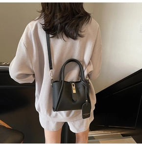 Detail of black lychee grain leather bucket bag with gold lock and branded hangtag
