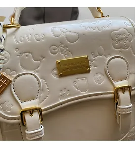Gros plan du sac en similicuir crème avec motifs embossés et détails métalliques dorés
