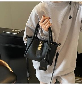Close-up of black lychee texture leather bucket bag with gold hardware and logo tag