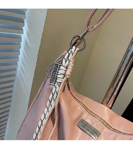 Detail of pink PU leather shoulder bag with woven rope zipper charm and metal heart tag