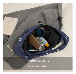 Détail de la capacité intérieure du sac cabas en denim bleu avec broderie cerise