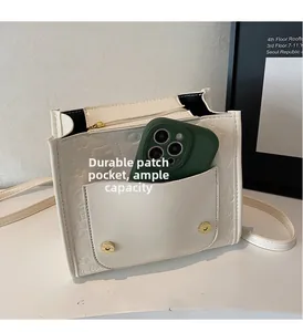 Détail de la poche latérale du sac à dos en cuir blanc contenant un smartphone vert