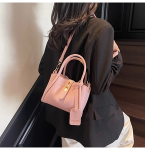Pink lychee grain leather bucket bag with gold lock shown from a side-view on a model