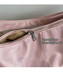 Detail of pink PU leather bag featuring a smooth silver metal zipper and beige fabric lining