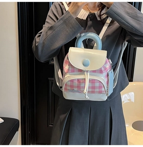 Detailed close-up of a mini pink and white checkered backpack with a blue handle on a model