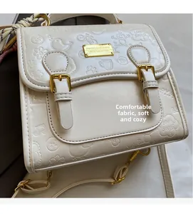 Détail du sac en cuir blanc crème avec gaufrage dessin animé et boucle en métal doré
