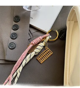 Détail d'un pendentif boulier doré avec cordons tressés sur un sac à main élégant