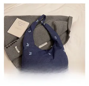 Détail du sac cabas en denim bleu avec broderies cerises et bandoulière intégrée