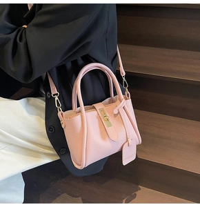 Close-up of a pink mini bucket bag with gold lock buckle and lychee leather texture