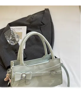 Dettaglio della borsa verde menta con fiocco decorativo e finiture metalliche ad anello