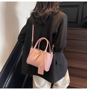 Detail of pink lychee leather bucket bag with gold hardware worn on shoulder