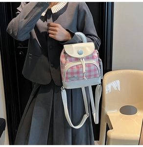 Close-up of mini pink plaid backpack with white leather flap on female model