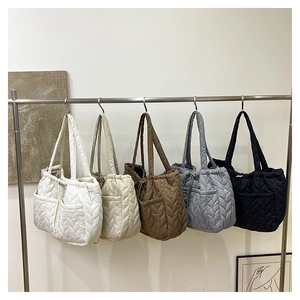 Macro view of five colors of quilted tote bags hanging on a rack for storage detail
