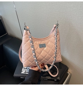 Detail of light pink quilted leather bucket bag with silver chain strap and metal clasp