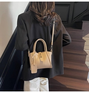 Modern beige bucket bag with pebbled leather texture and gold hardware on a model