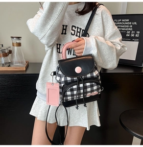 Detail view of mini black and white checkered backpack with pink handle and leather trim