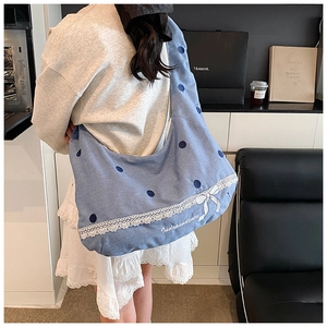 Détail d'un sac fourre-tout en denim bleu clair avec pois et nœud en dentelle blanche
