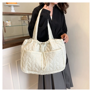 Close-up of cream white quilted tote bag showing wave stitching and silver drawstring detail
