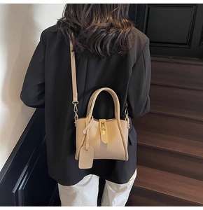 Detail of beige lychee grain leather bucket bag with gold clasp and shoulder strap