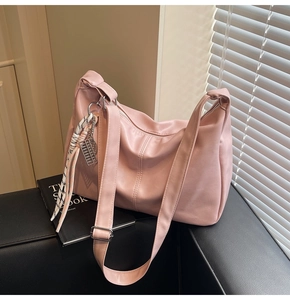 Detail of pink hobo bag with wide shoulder strap, silver buckle and plaid ribbon charm