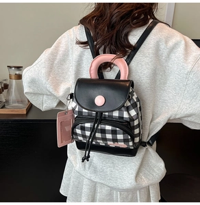 Rear view of a model wearing a mini plaid backpack with pink handle and ID card charm