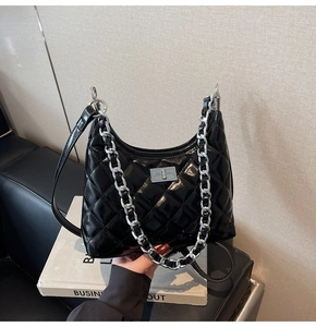 Detail of black quilted bucket bag with silver chain strap and metal turn-lock closure