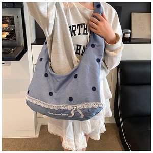 Détail du sac hobo en jean à pois bleus avec bordure en dentelle blanche et nœud