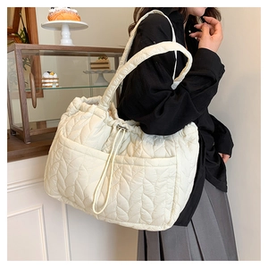 Quilted tote bag in cream white showing drawstring closure and spacious side pocket