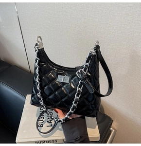 Detail of black quilted leather shoulder bag featuring silver chain and metal twist lock