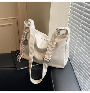 Detail of white PU leather bag featuring soft texture, wide strap, and silk scarf charm