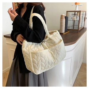 Detail of cream quilted tote bag featuring leaf-vein stitching and drawstring closure