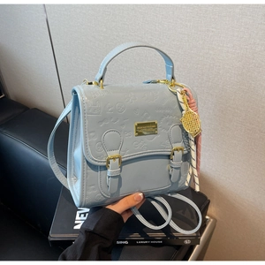 Détail d'un sac à main bleu clair avec motifs de dessins animés gaufrés et pendentif tennis