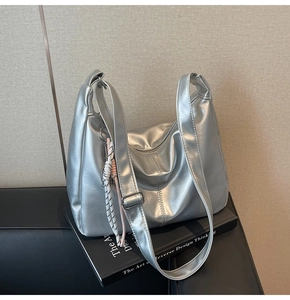 Detail of silver metallic hobo bag on books showing adjustable strap and texture