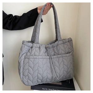 Detail of light gray quilted tote bag with leaf pattern and practical front pockets