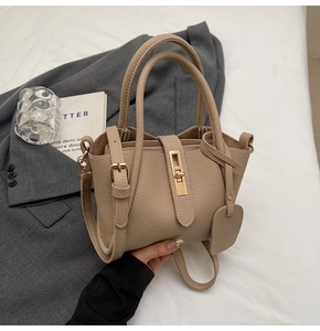 Detail of apricot bucket bag with lychee texture leather and gold metal twist lock