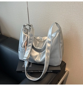 Detailed close-up of a silver metallic Hobo bag with wide strap and woven decoration