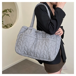 Detail of grey quilted tote bag with leaf pattern stitching and drawstring side pocket