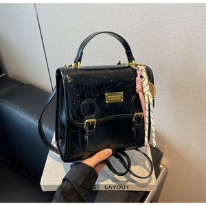 Détail du sac à dos en cuir PU noir gaufré avec boucles dorées et breloque tissée