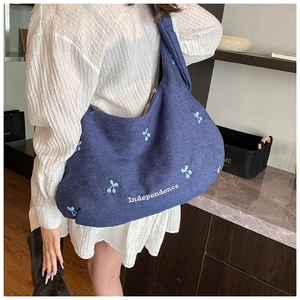 Détail du sac hobo en denim bleu avec broderie Independence et patchs floraux