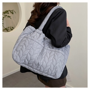 Close-up of a grey quilted puffer tote bag with unique leaf-vein pattern and wide strap
