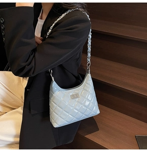 Close-up of light blue quilted leather bag featuring a silver metal twist lock and chain strap
