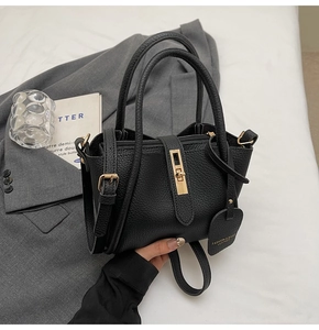 Close-up of black lychee grain leather bucket bag with elegant gold metal twist lock