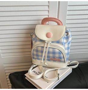Detail of blue gingham mini backpack with pink handle and apple logo on white book