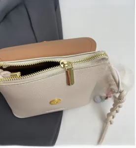 Detail of smooth gold zipper and magnetic buckle on beige crossbody bucket bag