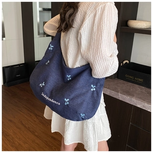 Détail du sac cabas en denim avec broderies de cerises bleues et lettrage blanc