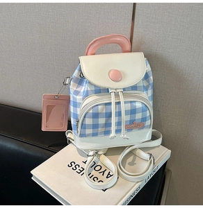 Detail view of a blue checkered mini backpack with pink apple tag and matching card holder