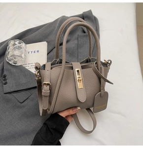 Detail shot of grey bucket bag with pebbled leather texture and golden twist lock closure