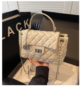 Detail of beige quilted leather bag with metallic swivel lock and chain strap