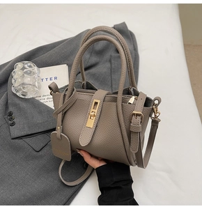 Detail view of taupe lychee leather bucket bag featuring gold buckle and crossbody strap