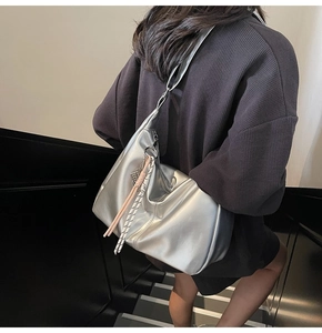 Detail view of silver leather crossbody bag with tassel charms and metal chain strap